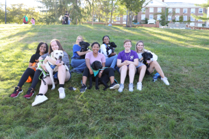 Hartwick students smile with five Labrador retrievers